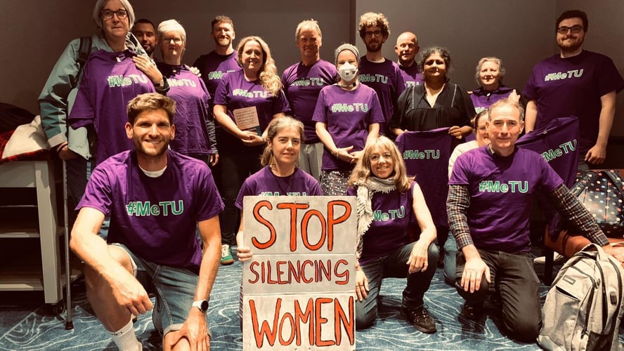 Group of #MeTU activists and person at the front holding a placard reading 'stop silencing women'